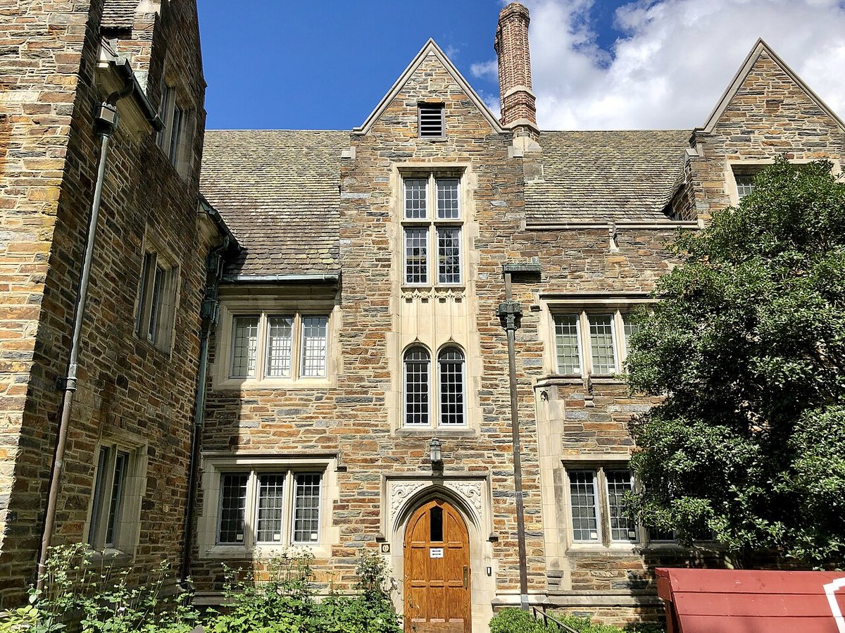 Stone university building with tall windows under a blue sky